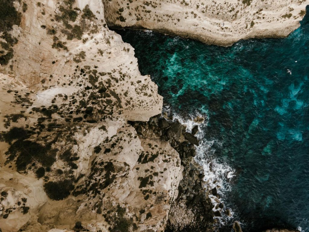 Breathtaking aerial photograph of Malta's steep cliffs and vibrant turquoise sea, showcasing dramatic waves.