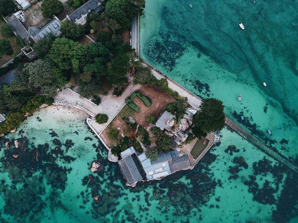 A breathtaking aerial shot of a secluded coastal peninsula surrounded by clear turquoise waters.