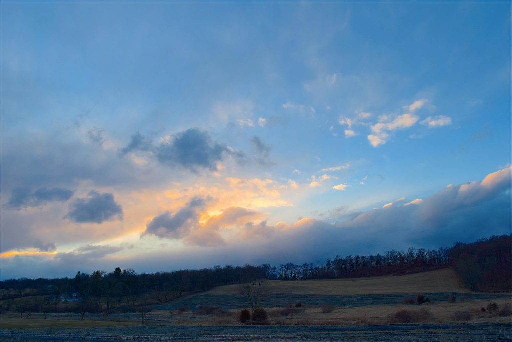 Scenic rural landscape with a stunning sunset and expansive cloud-filled sky.