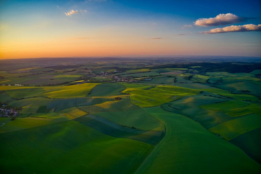 A stunning aerial view of green fields and rolling hills in Bucovice, Czech Republic at sunset.