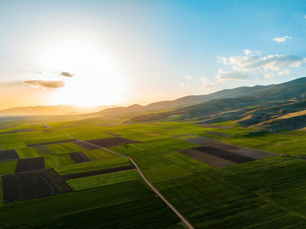 Captivating aerial landscape of lush fields and hills at sunset, perfect for highlighting rural beauty.