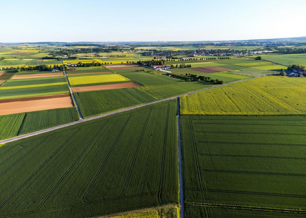 Expansive aerial view of colorful agricultural fields divided into grids under clear blue skies.