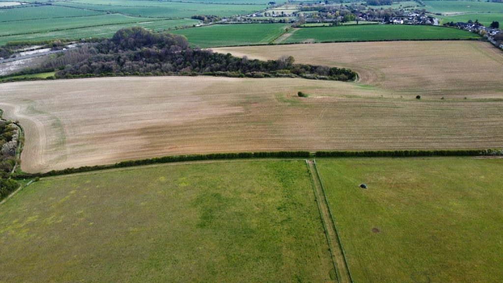 Aerial shot of lush green and brown agricultural fields in Sharpenhoe, England