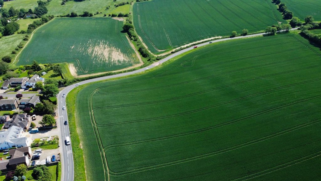 Drone captures expansive farmland and roads weaving through Streatley, UK, on a sunny day.