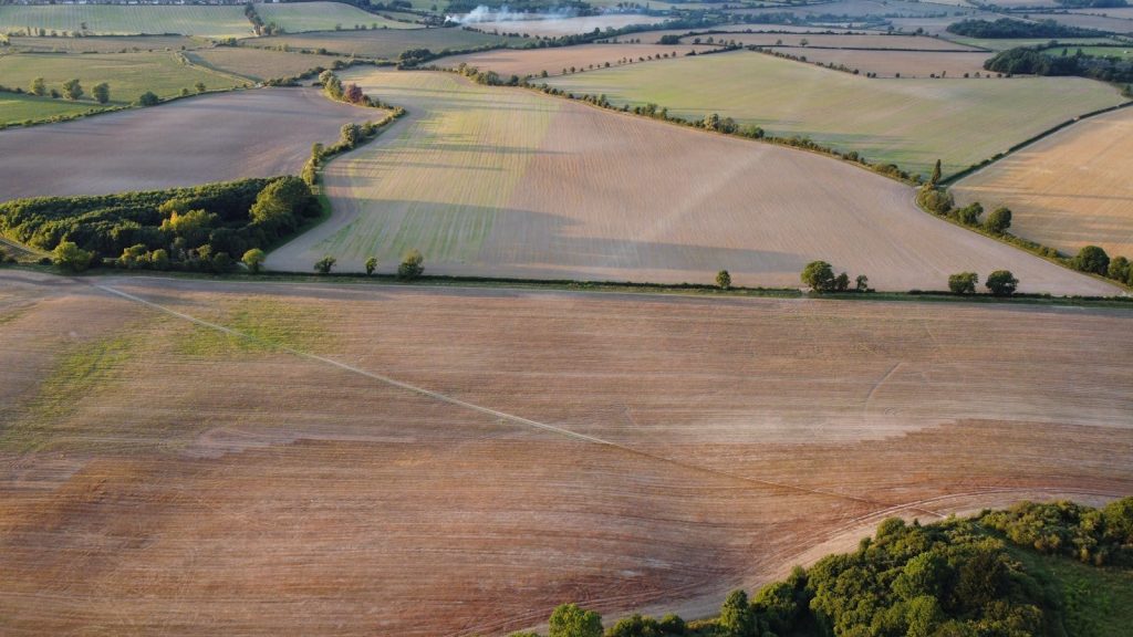 Drone capture of expansive rural fields in Central Bedfordshire, England at sunset.