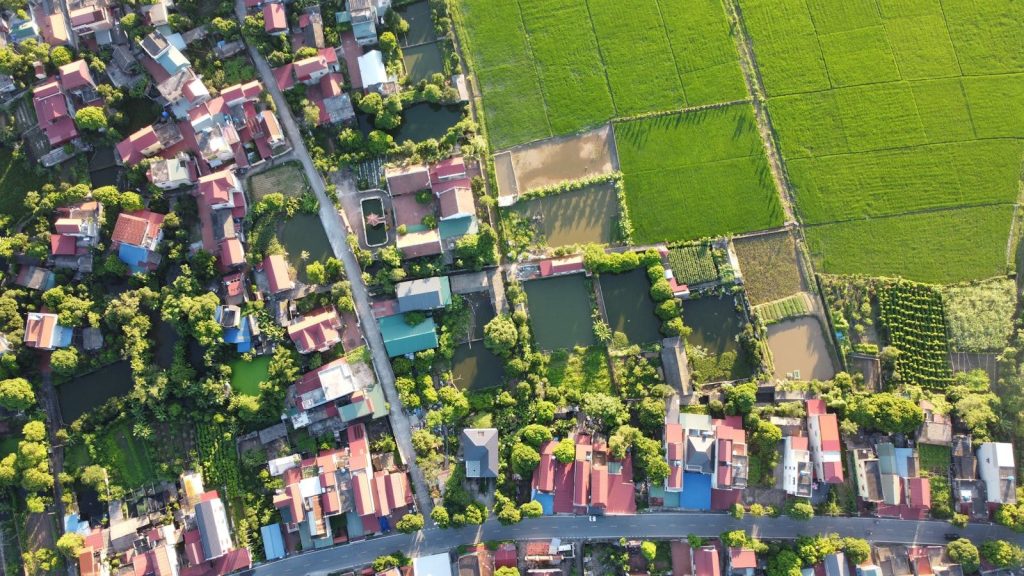 Aerial shot capturing a Vietnamese village surrounded by lush green rice fields.