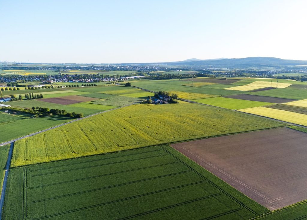 A stunning aerial view showcasing colorful patchwork farmlands under a clear blue sky.