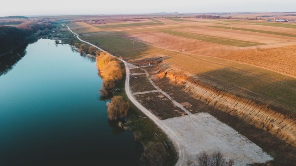 Beautiful aerial view of Olosig, Romania with a scenic river and vast fields.
