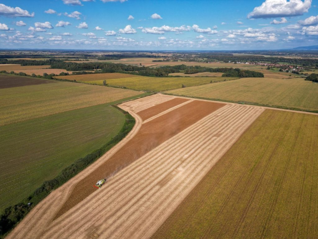 Drone aerial view of expansive agricultural fields in Garešnica, Croatia under a clear blue summer sky.