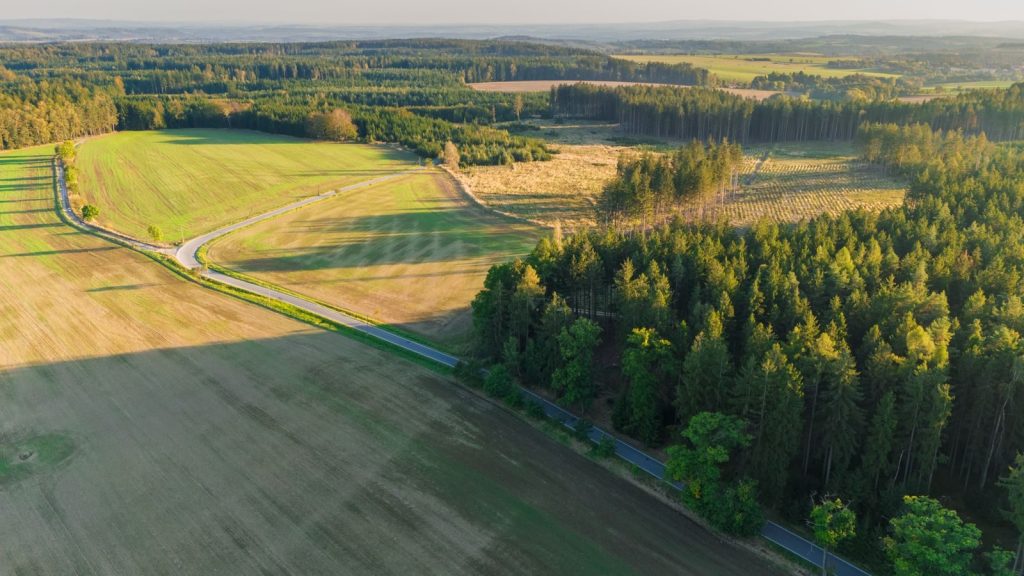Aerial view of lush green fields and forests in the Czech countryside during daytime.