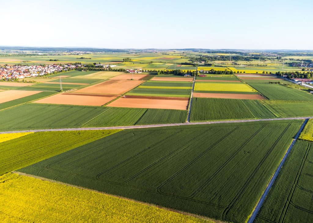 Stunning aerial view of vibrant patchwork agricultural fields and a distant village.