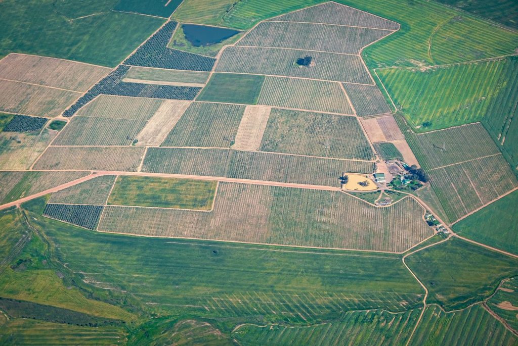 High-angle shot of vast agricultural lands with varying crop patterns in the countryside.
