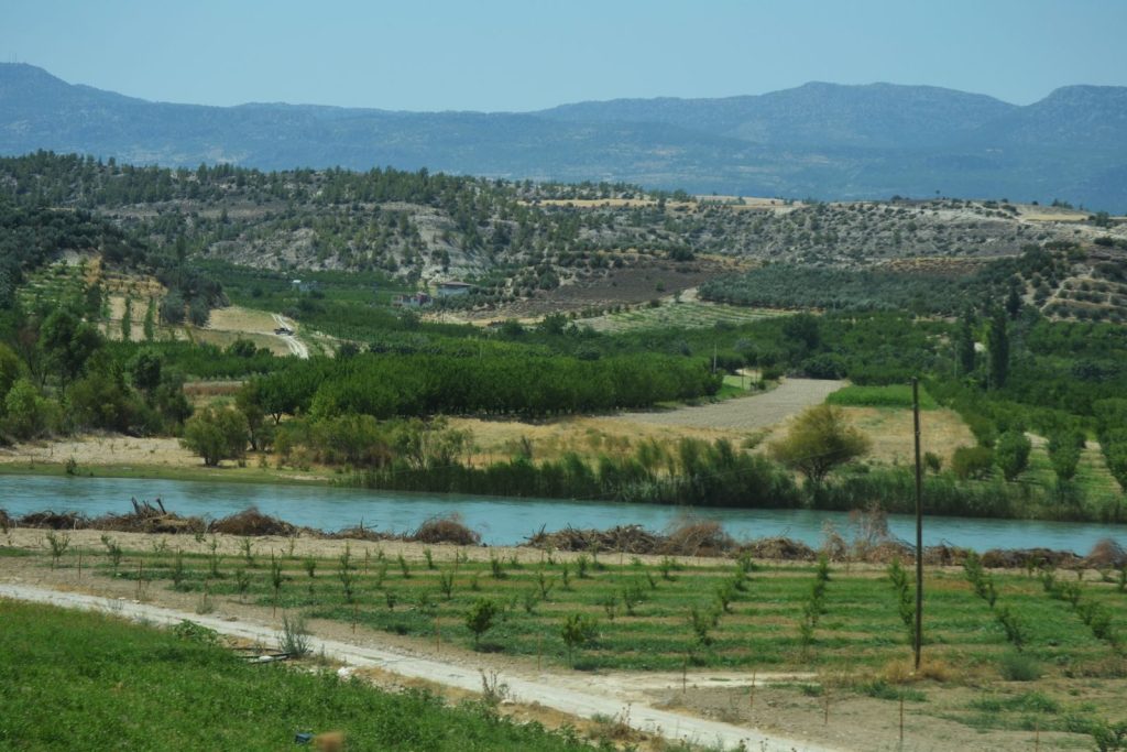 Panoramic landscape of lush fields and a winding river under clear skies.